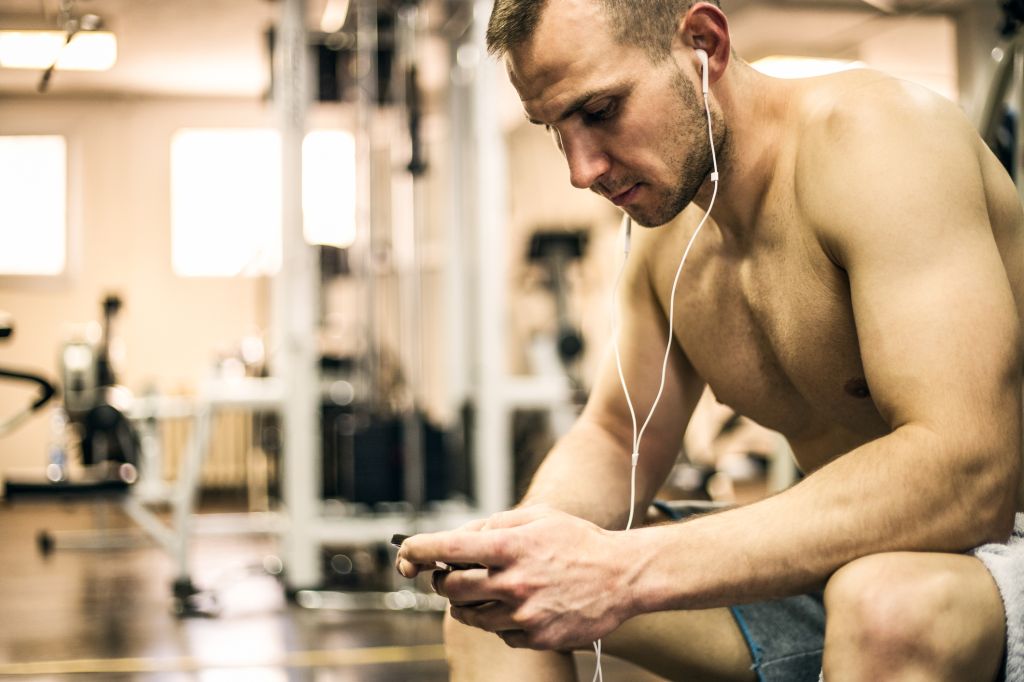 Sportsman in the gym texting on smartphone